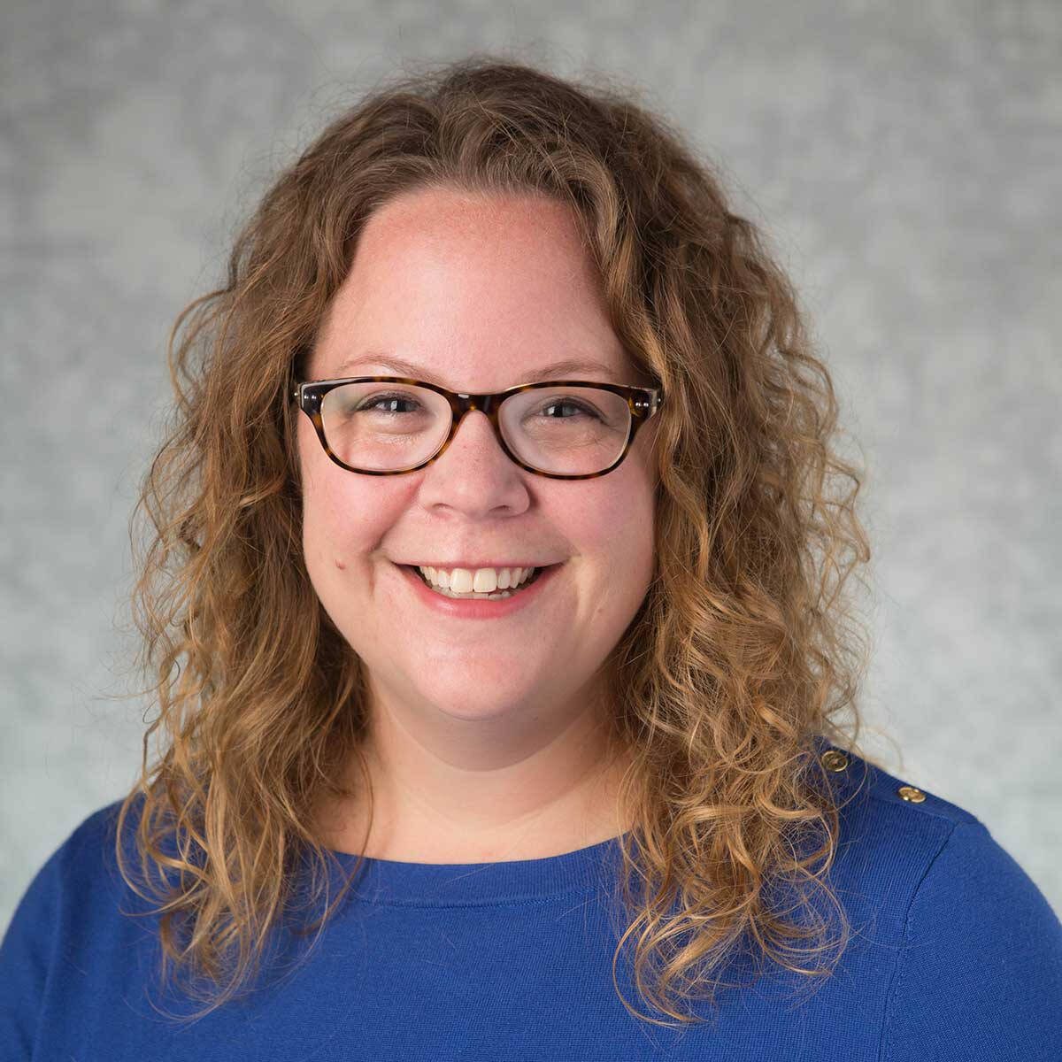 Dr. Stolley wearing a blue top and tortoise shell glasses